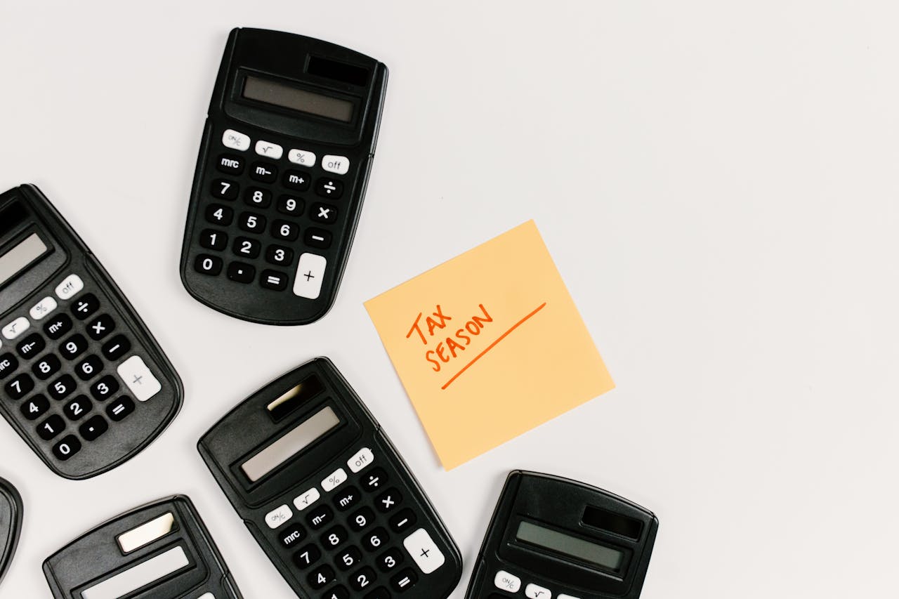 Top view of calculators with a tax season sticky note on a white background.